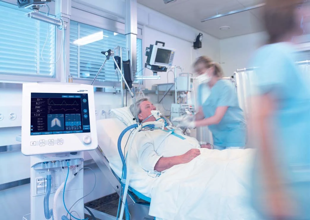 HAMILTON-G5 ventilator beside a patient and clinical staff in an intensive-care setting