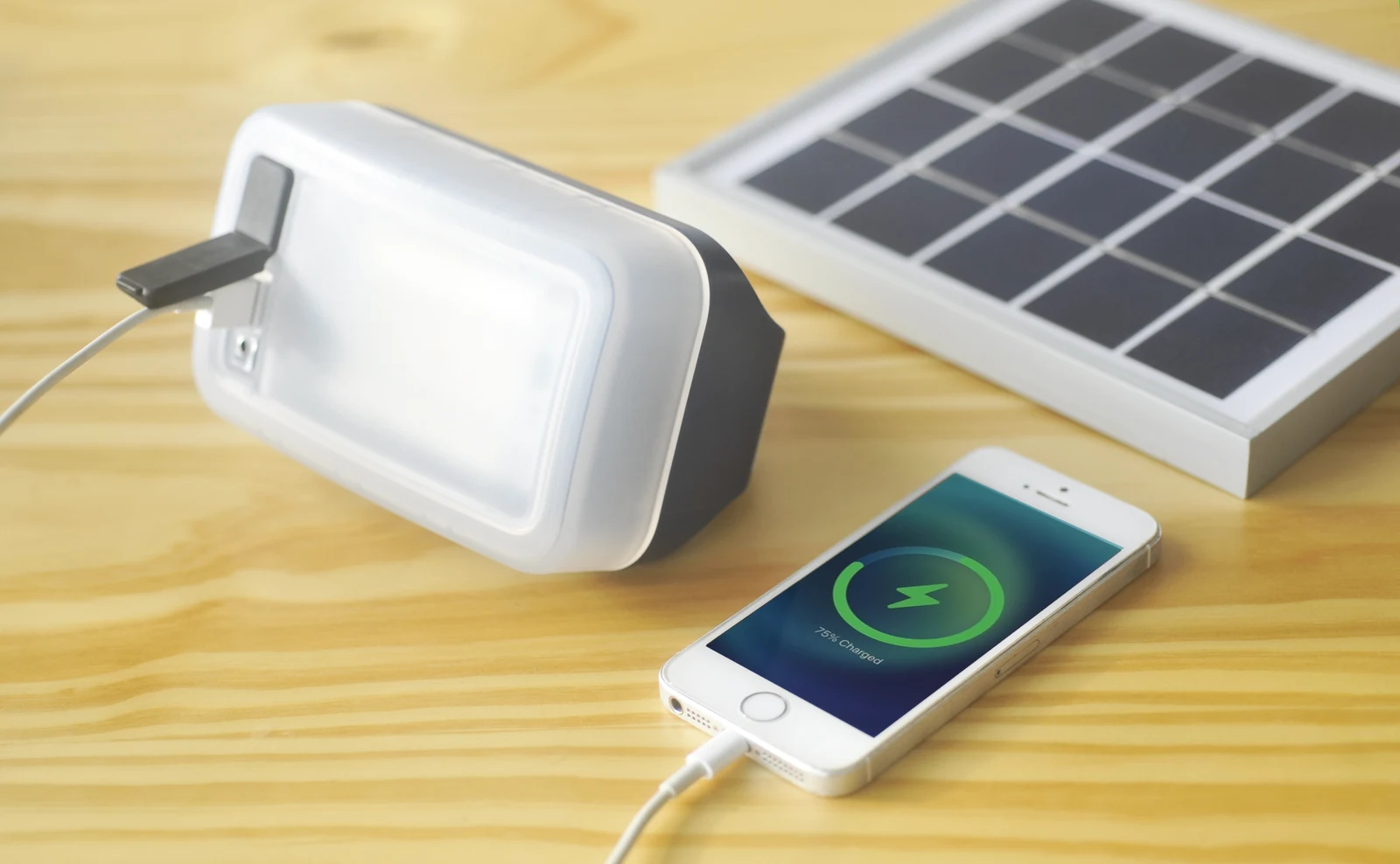 IONA ECO COMFORT lantern resting horizontally and charging a smartphone beside its solar panel