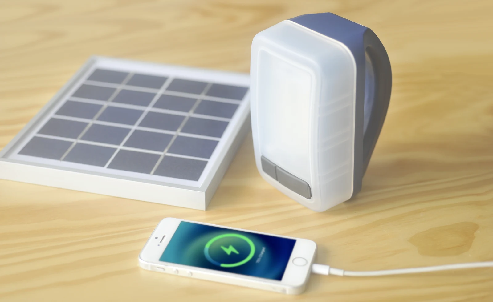 IONA ECO COMFORT solar lantern standing beside its solar panel and charging a smartphone