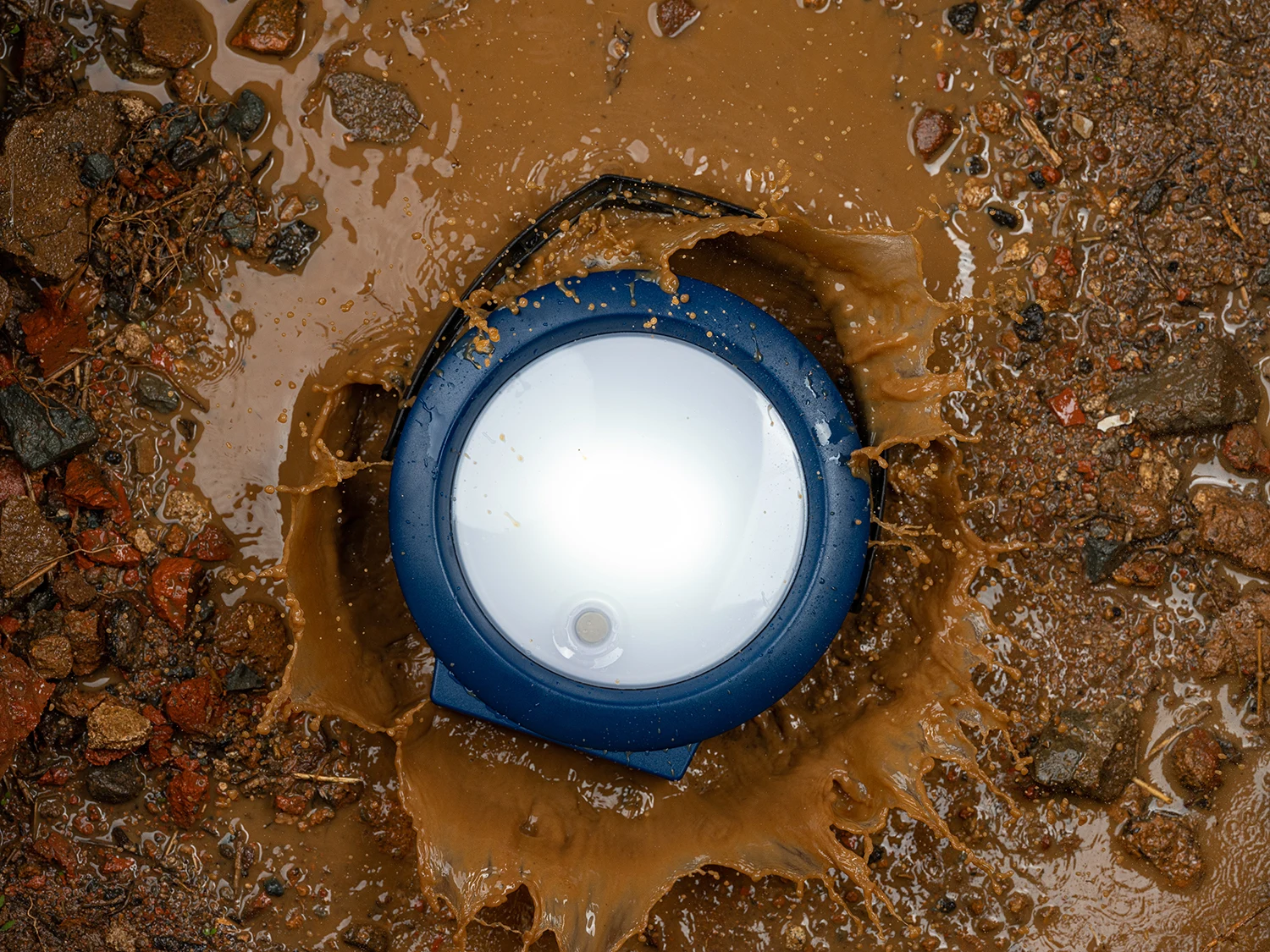 NIWA MULTI 300 XL solar lantern photographed lying in muddy water with splashes around it
