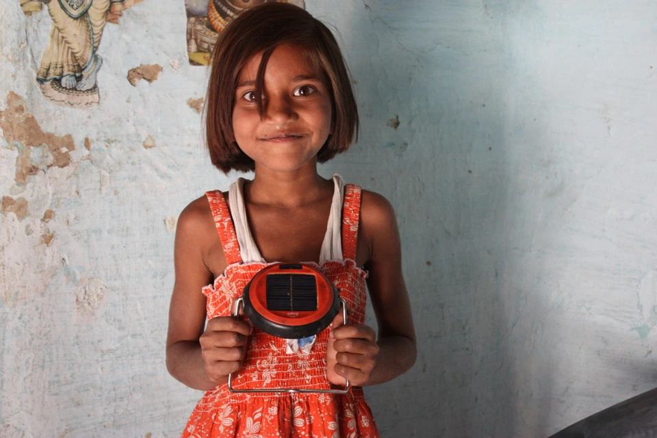 A child holding the red d.light S1 all-in-one solar light
