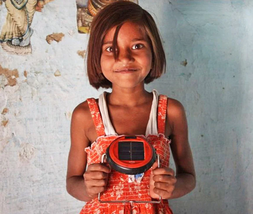 A child holding the red d.light S1 solar light with its integrated panel and wire stand